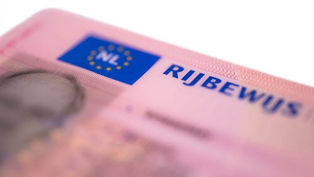 New Dutch pink driver's license in credit card format isolated on white background. Focus on on the first letters of the word RIJBEWIJS (drivers licence)
